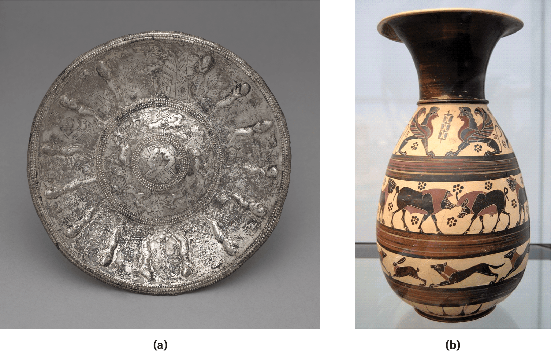 Two images of a bowl and jug are shown. The (a) faded silver bowl is round and shown standing up on a gray background. The outer perimeter is not smooth and shows small circles all around the bowl. Repetitive designs of leaves and people run on the outer circle. The next inner circle repeats designs of animals, leaves, and fowl. The final inner circle shows two figures facing each other. Small circles of tiny dots separate the three rings. (b) An image of a jug is shown on a flat gray surface with a gray background. The jug is fluted at the top with a short black neck. The bottom of the jug is pear shaped and has four rows of scenes depicted on a beige background and six-petaled black flowers strewn in the first two rows. Brown, red, and black stripes separate the rows of scenes. The top row shows two winged creatures with four paws each and a human looking head with long curly black hair. The wings show multi-colored feathers in black and brown and a long thin tail is seen at their hind ends. The next row shows large black animals with four legs and brown manes and underbellies with long snouts and large ears – two in the middle facing each other and two more at each end only showing their raised heads. The next row shows two long, thin, black animals with four paws, tails, and brown necks facing to the left and one with long ears and a bit smaller in front of them at the left. The last row shows a beige background with black lines.