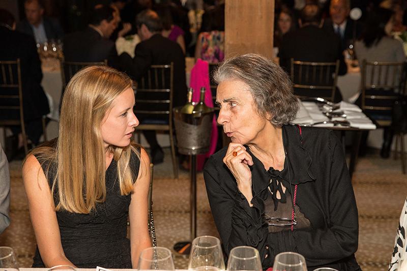 Two women engaged in conversation at a table set for a formal dinner.