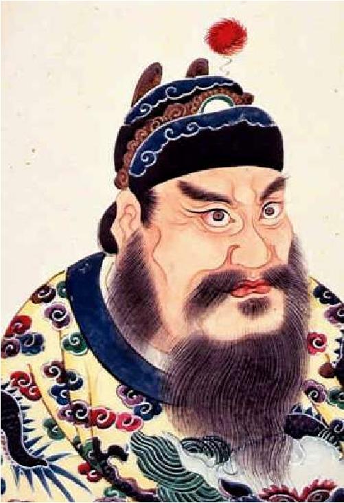 An image of a painting is shown on a pale yellow background. A large man is shown with pale skin, large, round, brown eyes, thick angled eyebrows and beard and moustache. He has a large flat nose, red lips, and a round ball of skin protrudes between his eyebrows. He wears a colorful hat in black, blue, brown, and white with a round fuzzy ball above his head at the right, attached by a zig-zag line to the hat. His shirt is yellow with a blue and white collar, and red, green, white, and blue flowery designs show all over.