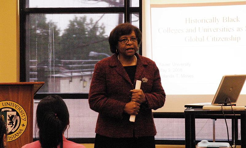 Woman in a suit speaking in front of a classroom.