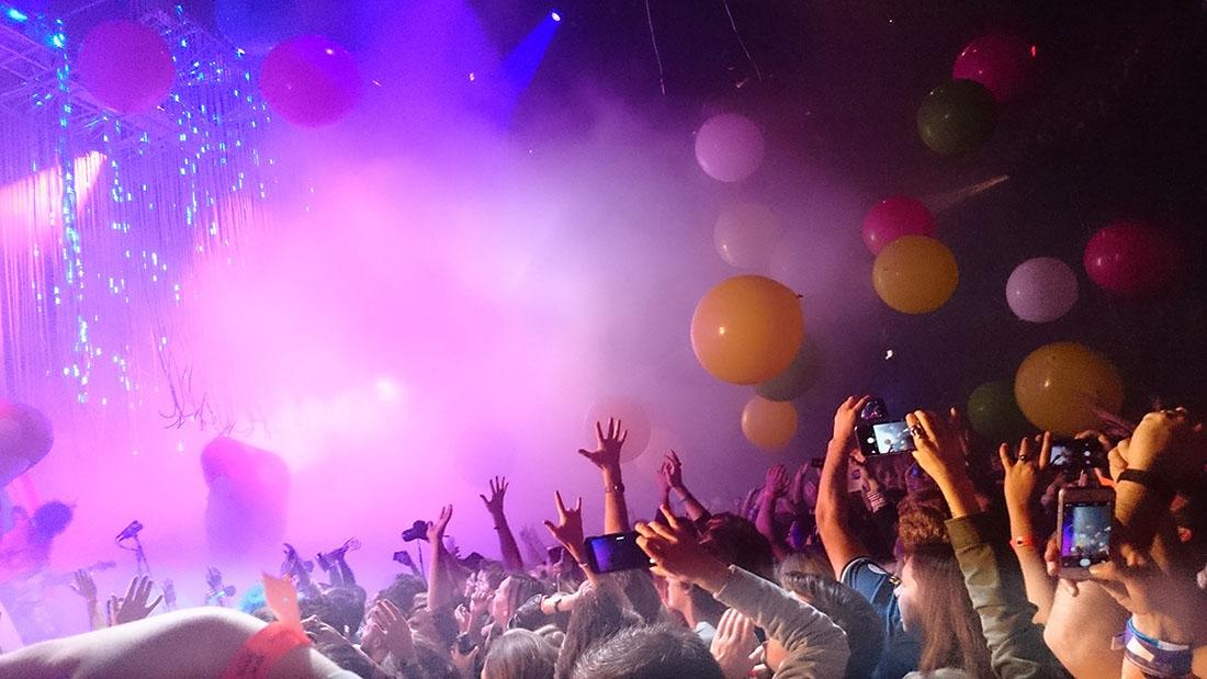 Many people stand with their hands and phones held up at a rock concert.