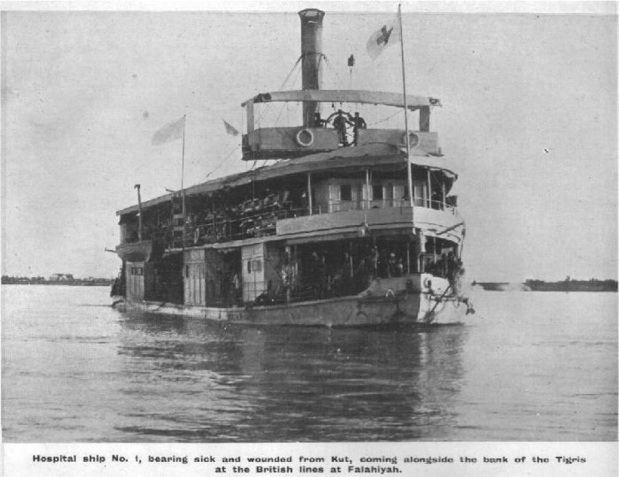 A photograph shows a large two-tiered ship in the water. The bottom floor shows many people standing on the outside of the ship while the top floor shows wounded soldiers laying on cots stacked atop each other. On top of the ship is a covered long platform with a large circle in the middle and three men standing in front of the circle. A white flag with a red cross flies at the front and a large tall smokestack is shown behind the platform. A cityscape is shown in the background. At the bottom of the photograph are the words “Hospital ship No. 1, bearing sic and wounded from Kut, coming alongside the bank of the Tigris at the British lines at Falahiyah.”