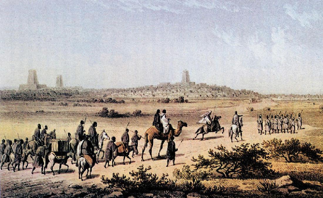 An image is shown of blue sky over the background of a large tiered stone city with three large towers. In front of the far away city is landscape with sparse green bushes. In the front is a caravan of people walking and riding animals – horses, camels, and donkeys. The people are heading to the right, wearing long white or dark robes, carrying spears, and dark skin. No facial features are seen. In front of them at the right, stand a group of people in white short robes, wearing helmets, and holding spears. In the right foreground are short, dark bushes on the dark brown landscape.