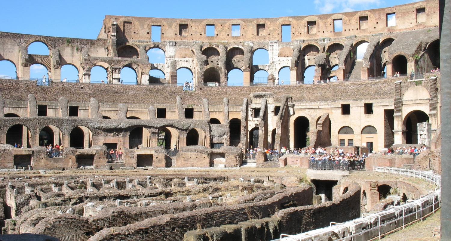 Very large stone structure in ruins. Visible are various levels of seating and a large central performance area.