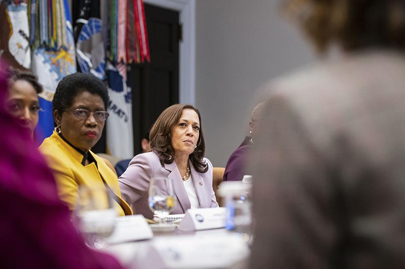 Several women in business suits seated around a conference table.