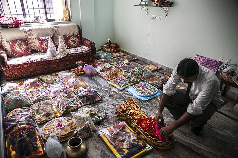 A man examining many items of a woman's dowery displayed on the floor of a living room.