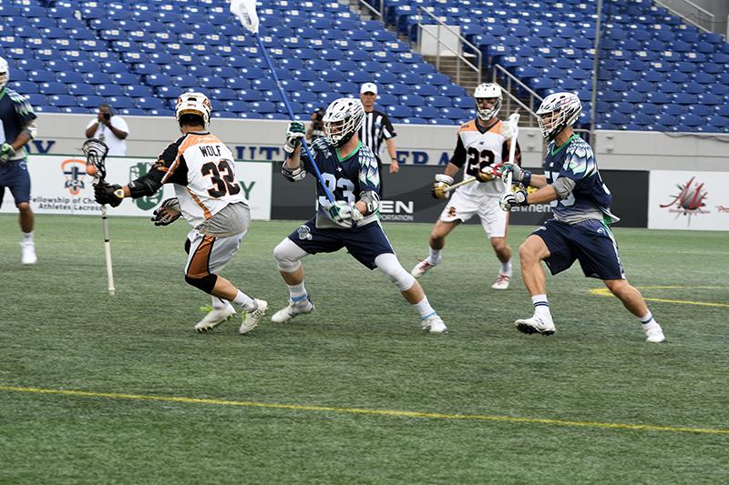 Lacrosse players wearing professional uniforms and helmets in the middle of a game.