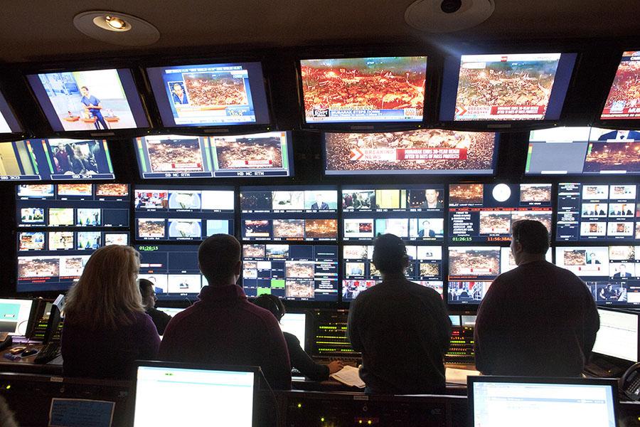 A room filled with screens and people monitoring the different activity on each screen.