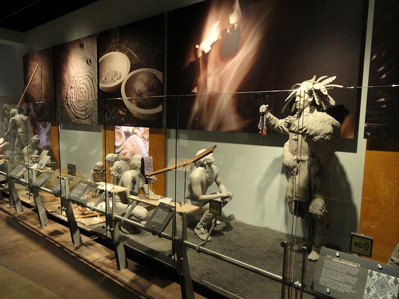 Diorama of Native Americans in the Indiana State Museum in Indianapolis, Indiana. Diorama consists of models of human beings posed doing various activities. Human models are monochrome and do not look like realistic depictions of people.